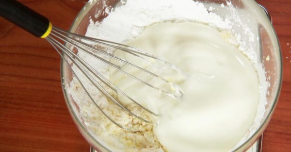 Ингредиенты для начинки йогуртового пирога в стеклянной миске с металлическим венчиком
