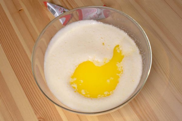 Растопленное сливочное масло в миске со смесью из йогурта, сахара и яиц