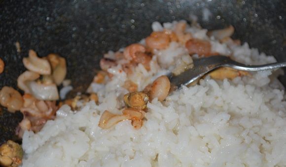 Отварной рис и морепродукты в сковороде с ложкой