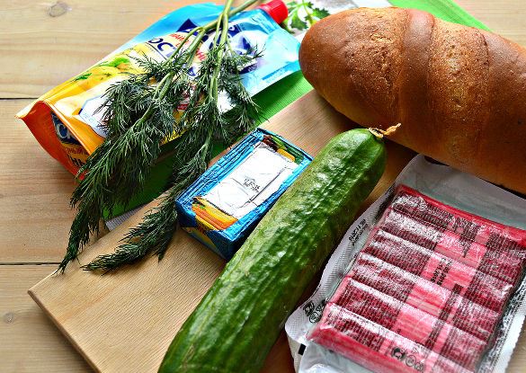 Продукты для приготовления бутербродов с плавленым сыром, огурцом и крабовыми палочками на столе