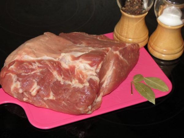Кусок сырого свиного мяса, лавровый лист, соль и чёрный перец горошком на столе