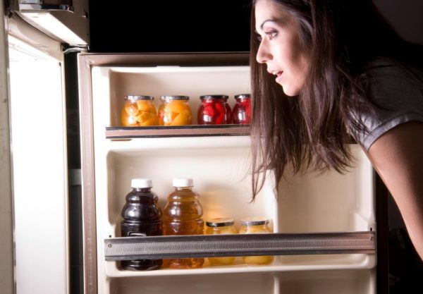 Девушка смотрит в холодильник