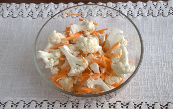 Кусочки сырой цветной капусты с морковью и чесноком в глубокой стеклянной миске