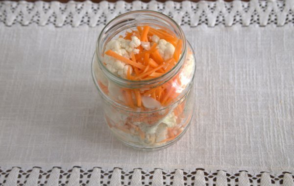 Кусочки цветной капусты, моркови и чеснока в стеклянной литровой банке