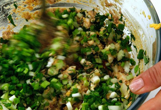 Перемешивание салата из печени трески и зелёного лука в стеклянной ёмкости