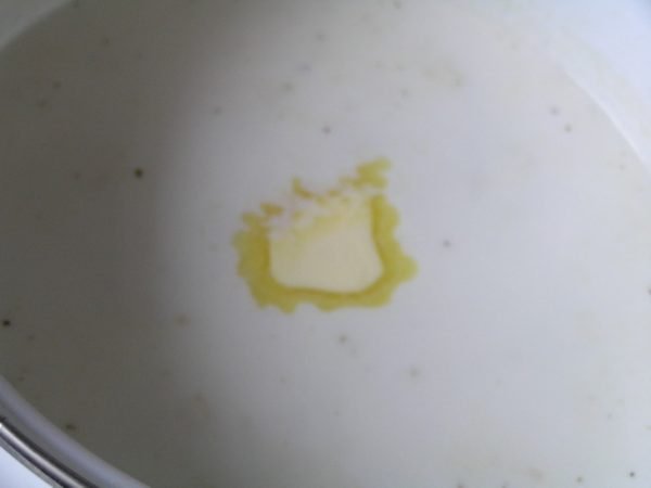 Кусочек сливочного масла в кастрюле с молочным супом